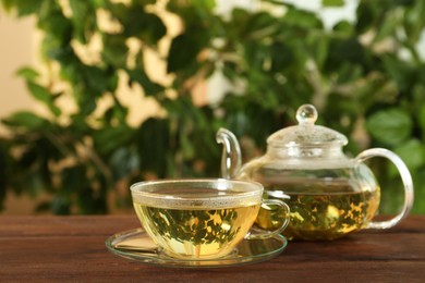 Photo of Fresh green tea in glass cup and teapot on wooden table