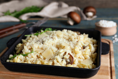 Photo of Delicious risotto with cheese and mushrooms on wooden board, closeup