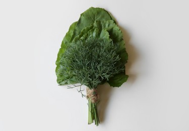 Photo of Bunch of dill and beetroot leaves on white wooden table, top view