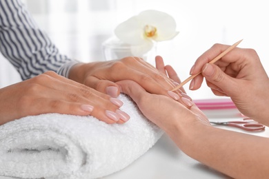 Manicurist preparing client's fingernail cuticles in salon, closeup