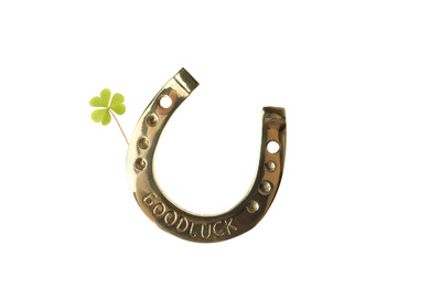 Golden horseshoe with phrase GOOD LUCK and clover on white background. St. Patrick's Day celebration