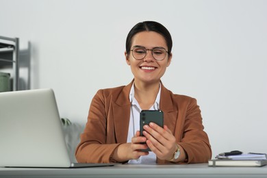 Young woman using smartphone at table in office