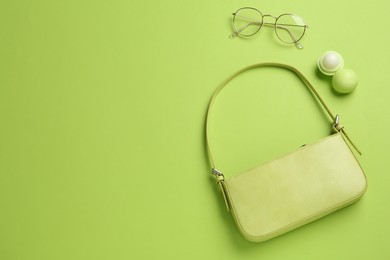 Stylish baguette bag, glasses and lip balm on light green background, flat lay, Space for text