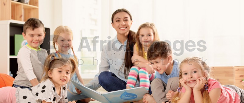 Kindergarten teacher reading book to children indoors. Banner design