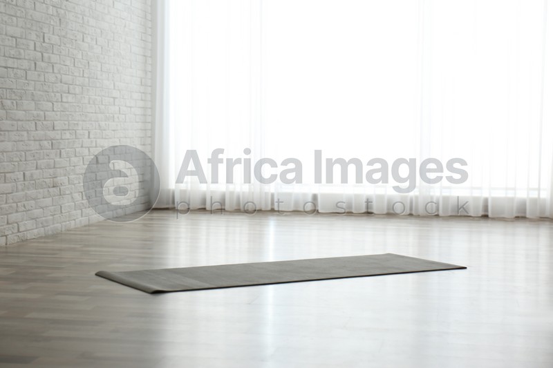 Photo of Unrolled grey yoga mat on floor in room