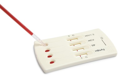 Dropping blood sample onto disposable express hepatitis test cassette with pipette on white background