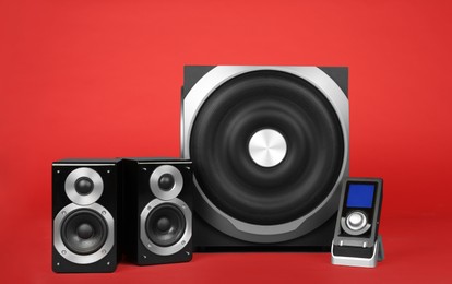 Modern powerful audio speaker system with remote on red background