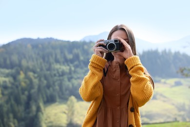 Woman taking photo with camera in mountains