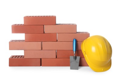 Photo of Many red bricks, hard hat and trowel on white background