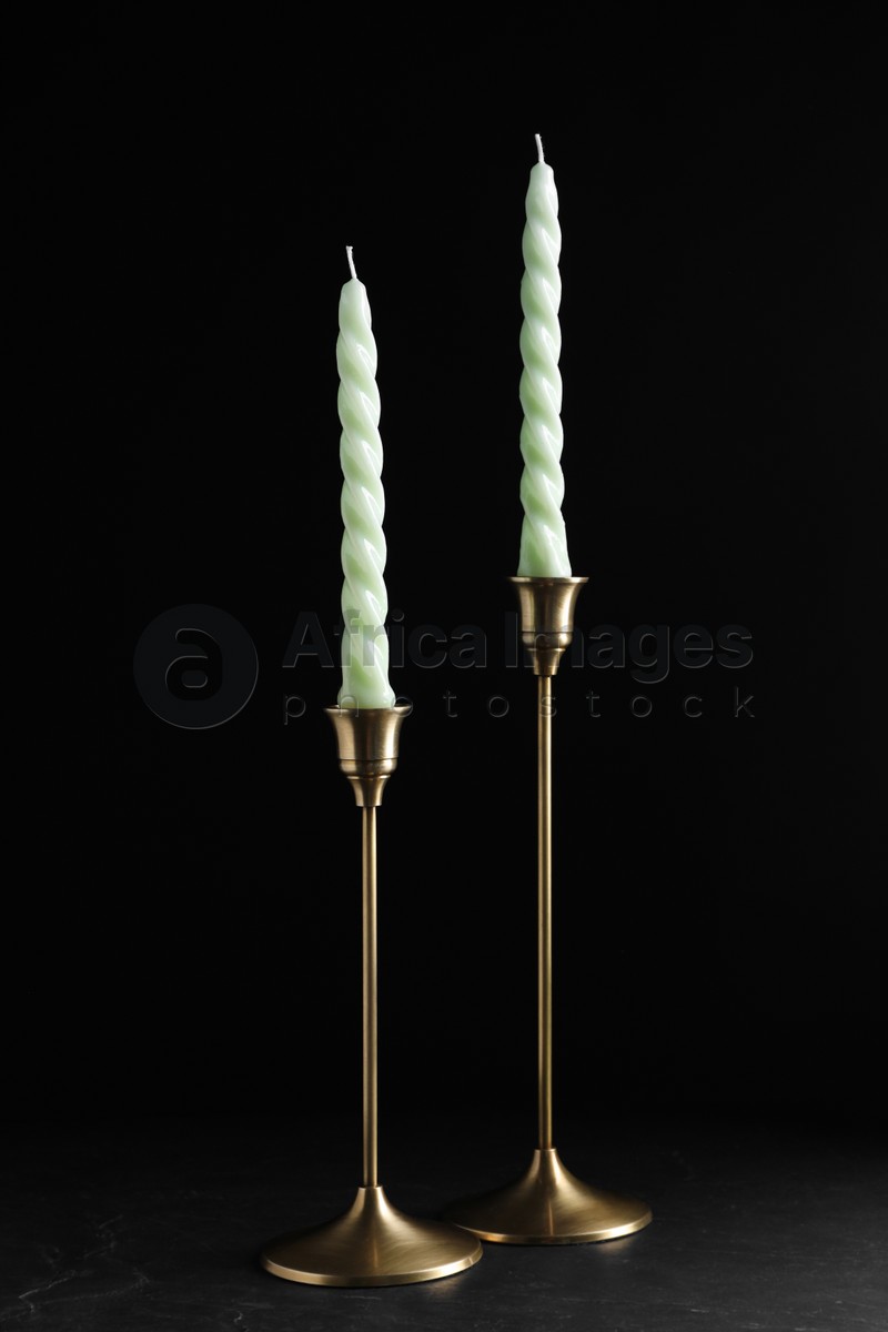 Vintage metal candlesticks with candles on table against black background