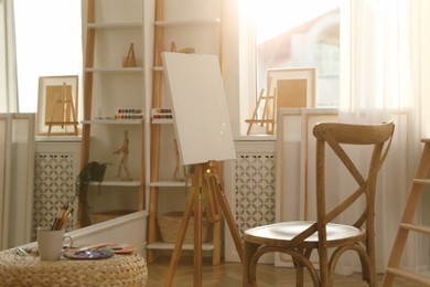 Photo of Blank canvas on easel in art studio