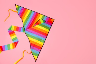 Bright rainbow kite on pink background, top view. Space for text