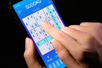 Woman playing sudoku game on smartphone, closeup