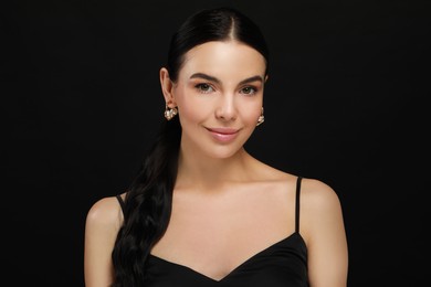 Young woman with elegant pearl earrings on black background