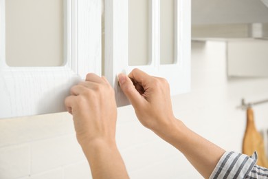 Photo of Woman opening cabinet doors at home, closeup