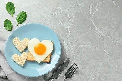 Romantic breakfast with heart shaped fried egg on served grey marble table, flat lay. Space for text