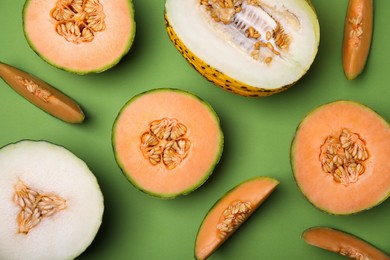 Cut different types of melons on green background, flat lay