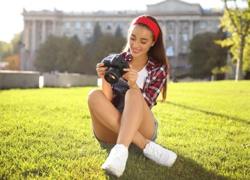 Young photographer with professional camera on green grass