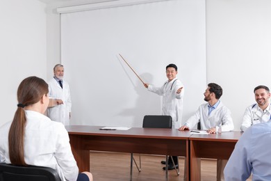 Photo of Doctors giving lecture near projection screen in conference room