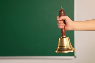 Pupil with school bell near chalkboard, closeup. Space for text