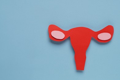 Photo of Woman's health. Paper uterus on light blue background, flat lay with space for text
