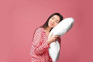 Beautiful Asian woman with pillow on dusty rose background. Bedtime