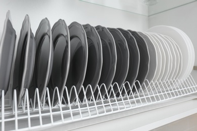 Drying rack with clean plates in kitchen cabinet, closeup