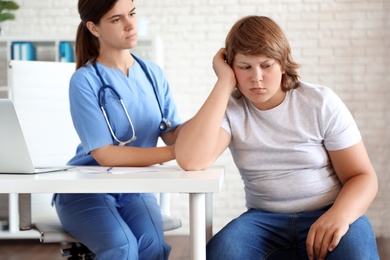 Emotional overweight boy consulting with doctor in clinic