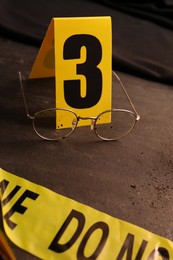 Crime scene marker and glasses on black slate table