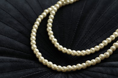Elegant necklace with pearls on black fabric, closeup