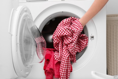Housewife putting clothes into washing machine