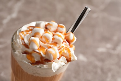 Glass with delicious caramel frappe on grey background, closeup