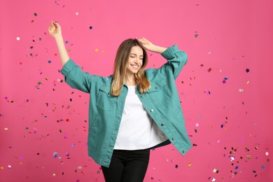 Happy woman and falling confetti on pink background