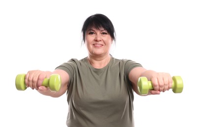 Happy overweight mature woman doing exercise with dumbbells on white background