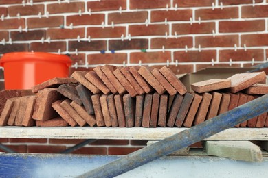 Many decorative bricks on scaffolding near wall. Tiles installation process