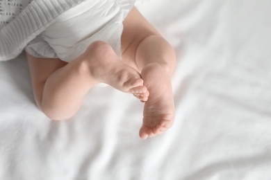 Little baby with cute feet on bed sheet, above view. Space for text