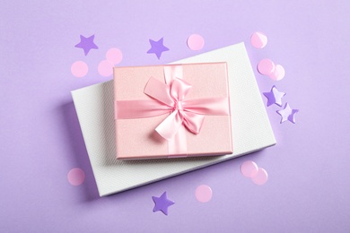 Photo of Beautiful gift boxes and confetti on violet background, flat lay