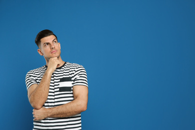 Pensive man on blue background, space for text. Thinking about answer to question