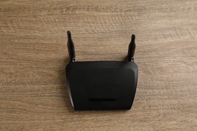 Modern Wi-Fi router on wooden background, top view