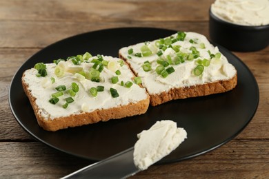 Photo of Delicious sandwiches with cream cheese and chives on wooden table