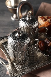 Photo of Tea, Turkish delight and date fruits served in vintage tea set on grey textured table, closeup