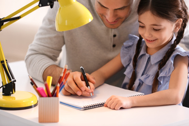 Man helping his daughter with homework at table indoors