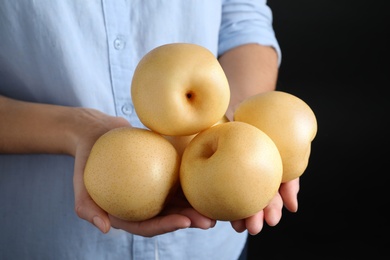 Woman holding ripe apple pears on black background, closeup
