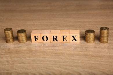 Word Forex made with cubes and stacked coins on wooden table, closeup