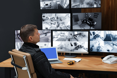 Security guard monitoring modern CCTV cameras indoors