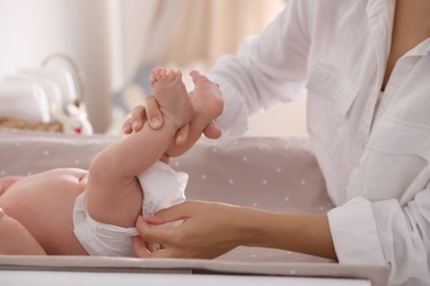 Photo of Mother changing her baby's diaper on table, closeup