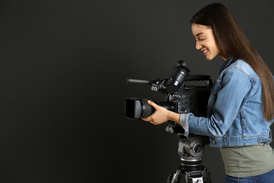 Operator with professional video camera on black background, space for text