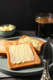 Photo of Delicious toasts served with butter and coffee on grey wooden table, closeup