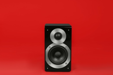 Modern powerful audio speaker on red background
