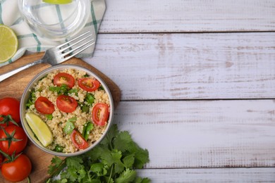 Photo of Delicious quinoa salad with tomatoes, parsley and lime served on white wooden table, flat lay. Space for text